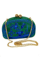 A green velvet clutch purse with blue floral embroidery, featuring a gold-tone metal clasp and a gold chain shoulder strap, set against a plain white background.